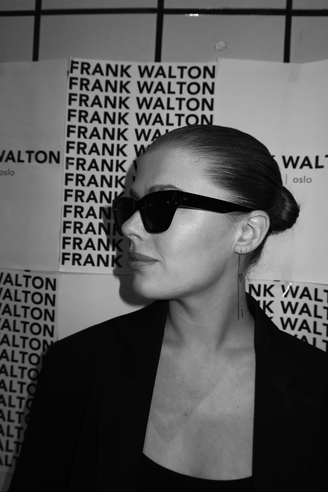 Creator i profil med solbriller foran Frank Walton-plakater
